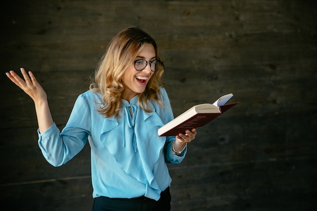 Mujer bonita emocionada riendo después de leer algo nuevo e interesante en el libro