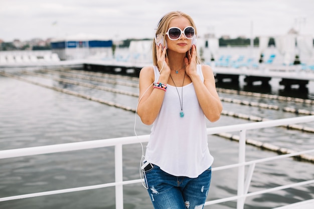 Mujer bonita escuchando música en el muelle