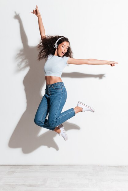 Mujer bonita escuchando música y saltando aislado