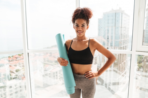 Mujer bonita con estera deportiva sonriendo