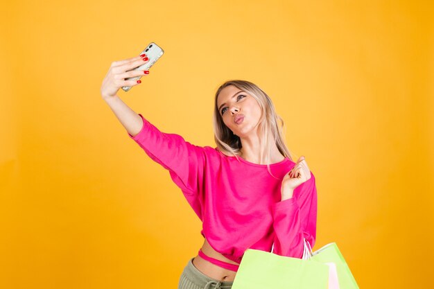 Mujer bonita europea en blusa rosa sobre pared amarilla