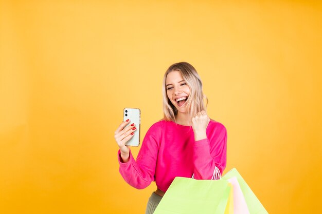 Mujer bonita europea en blusa rosa sobre pared amarilla