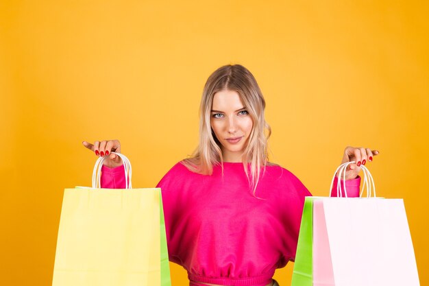 Mujer bonita europea en blusa rosa sobre pared amarilla