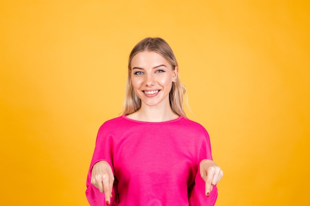 Mujer bonita europea en blusa rosa sobre pared amarilla