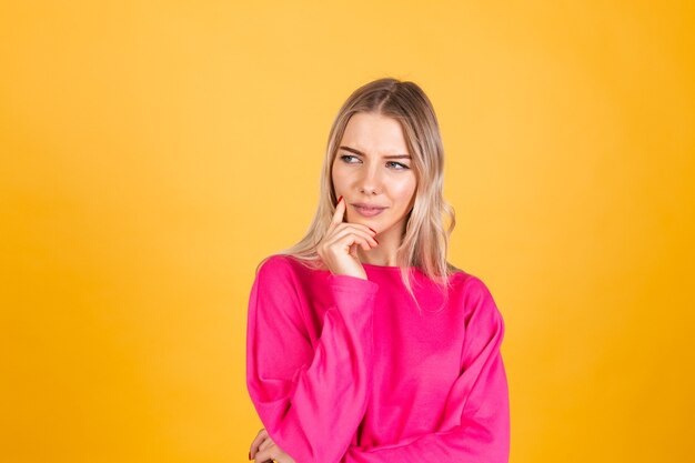 Mujer bonita europea en blusa rosa sobre pared amarilla