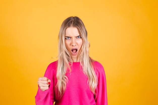 Mujer bonita europea en blusa rosa sobre pared amarilla