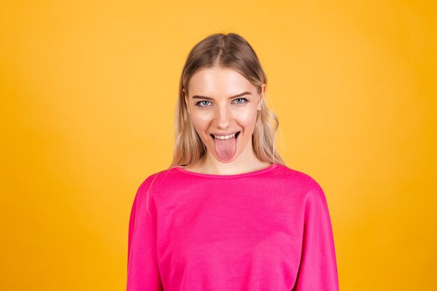 Mujer bonita europea en blusa rosa sobre pared amarilla