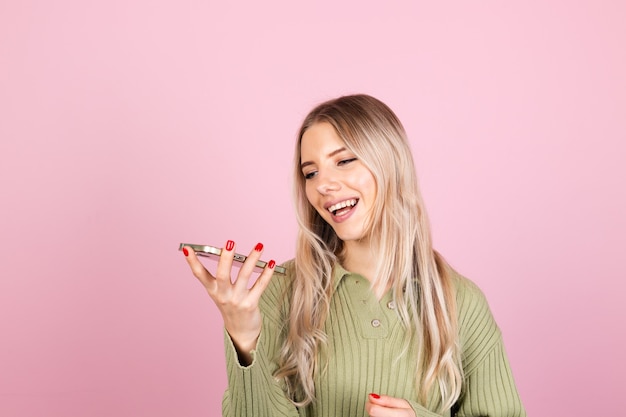 Mujer bonita europea en suéter casual en pared rosa