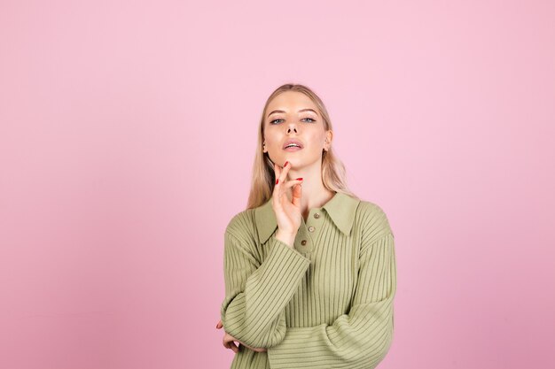 Mujer bonita europea en suéter casual en pared rosa