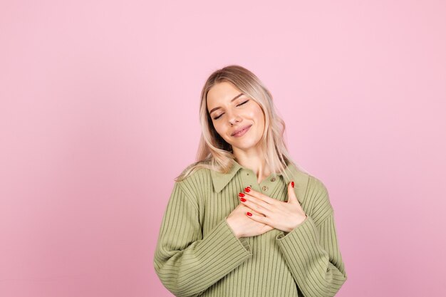 Mujer bonita europea en suéter casual en pared rosa