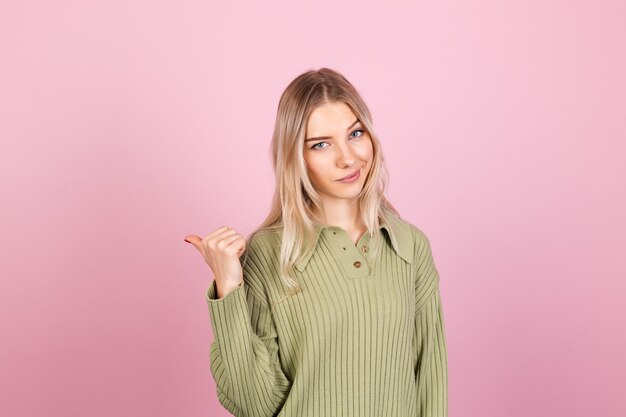 Mujer bonita europea en suéter casual en pared rosa