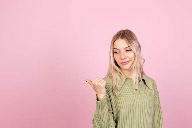 Mujer bonita europea en suéter casual en pared rosa