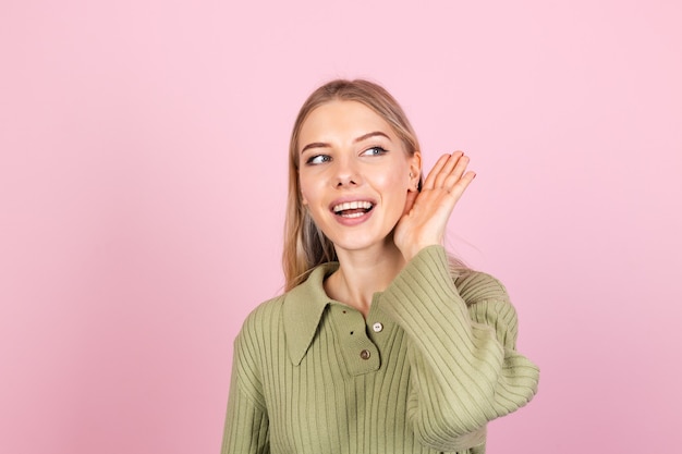 Mujer bonita europea en suéter casual en pared rosa