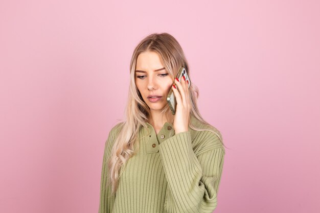 Mujer bonita europea en suéter de punto casual en pared rosa