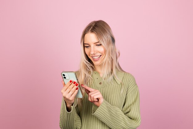 Mujer bonita europea en suéter de punto casual en pared rosa