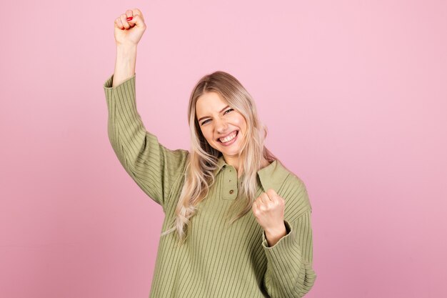 Mujer bonita europea en suéter de punto casual en pared rosa