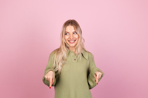 Mujer bonita europea en suéter de punto casual en pared rosa