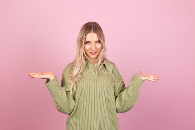 Mujer bonita europea en suéter de punto casual en pared rosa