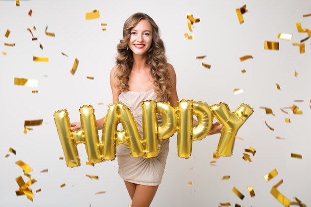 Mujer bonita feliz celebrando el año nuevo en confeti dorado