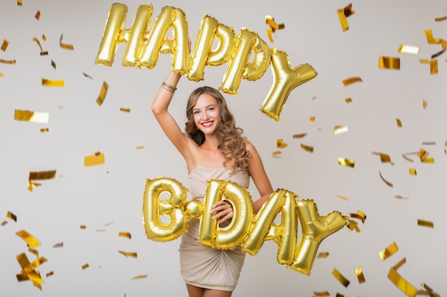 Mujer bonita feliz celebrando un cumpleaños en confeti dorado