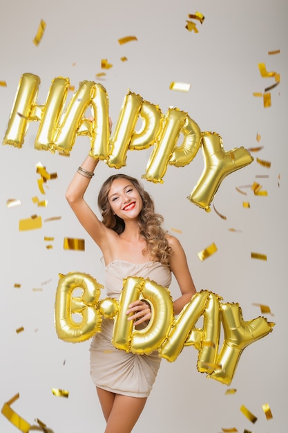 Mujer bonita feliz celebrando un cumpleaños en confeti dorado