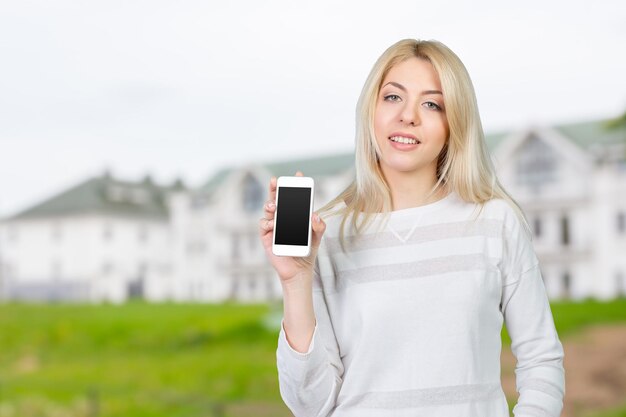 Mujer bonita feliz mostrando una pantalla de teléfono inteligente en blanco