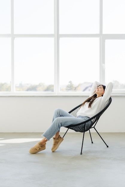 Mujer bonita feliz tumbada en el sillón el fin de semana