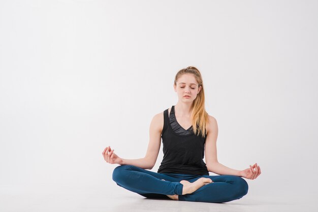 Mujer bonita haciendo yoga con los ojos cerrados