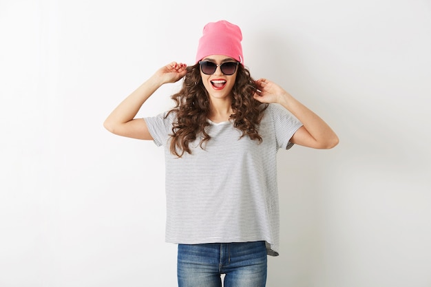 Mujer bonita hipster con sombrero rosa, gafas de sol, bailando feliz, cara sonriente, cabello largo, estado de ánimo positivo, emocional, traje de estilo hipster, tendencia de moda de verano, jeans y camiseta a rayas, aislado