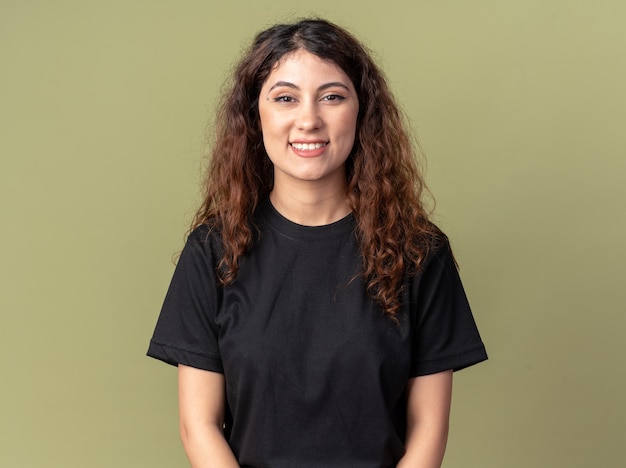 Mujer bonita joven alegre mirando al frente sonriendo aislado en la pared verde oliva