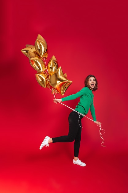 Mujer bonita joven alegre que sostiene los globos.