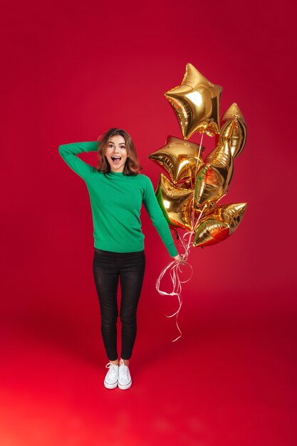 Mujer bonita joven alegre que sostiene los globos.