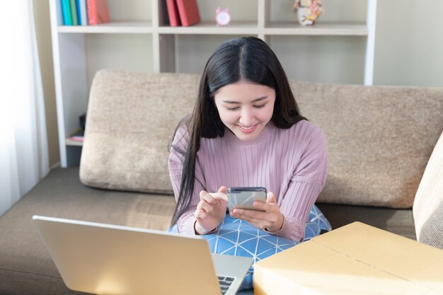 Mujer bonita joven alegre uso smartphone en la sala de estar