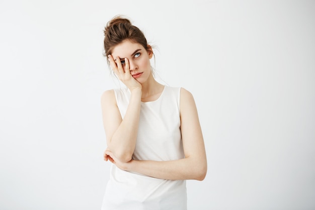 Mujer bonita joven cansada aburrida que oculta la cara detrás de las manos.