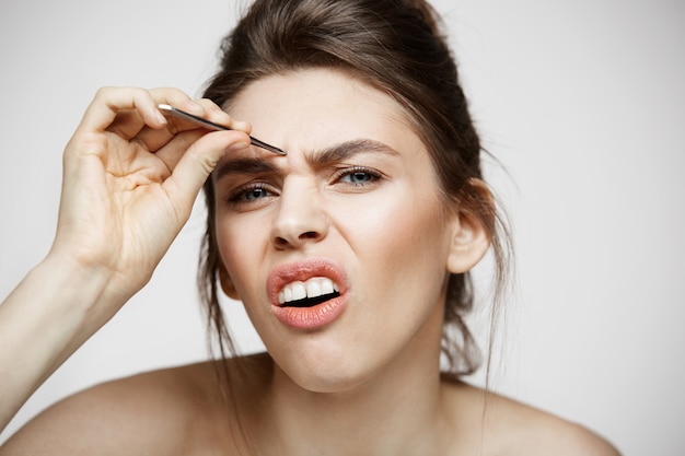 La mujer bonita joven con las cejas perfectas de la piel limpia pellizca la cara divertida. belleza y spa.