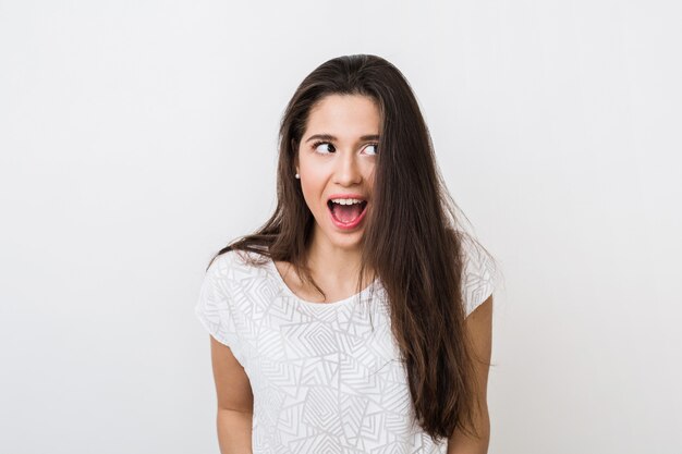 Mujer bonita joven con expresión de la cara divertida, boca abierta, ojos grandes, mirando a un lado, estado de ánimo sorprendido, emocional