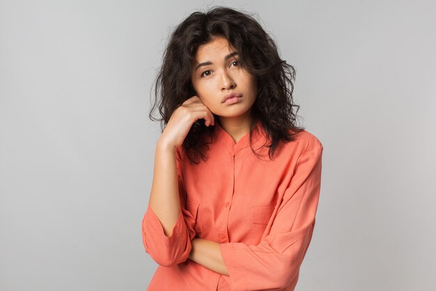 Mujer bonita joven con expresión de la cara melancólica, blusa naranja, aislado, triste emoción,