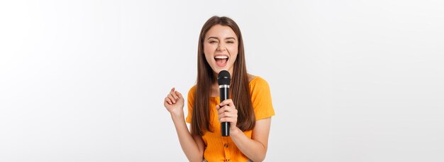 Mujer bonita joven feliz y motivada cantando una canción con un micrófono presentando un evento o teniendo