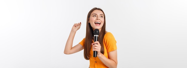 Mujer bonita joven feliz y motivada cantando una canción con un micrófono presentando un evento o teniendo