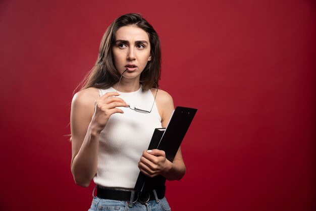 Mujer bonita joven con gafas sosteniendo cuadernos