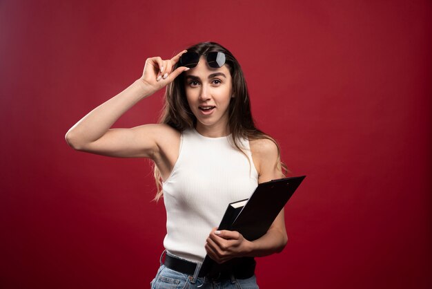 Mujer bonita joven con gafas sosteniendo cuadernos