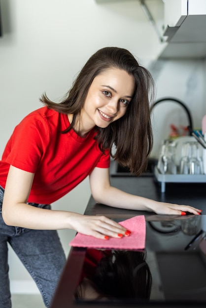 Mujer bonita joven haciendo quehaceres domésticos limpiando la cocina