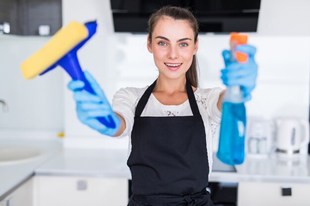 Mujer bonita joven hoding herramientas limpias de pie en la cocina