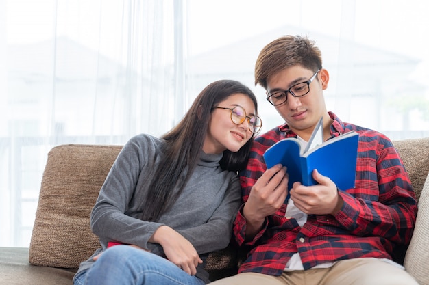 Mujer bonita joven y hombre guapo leyendo en el sofá