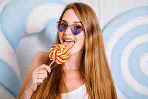 Foto gratuita mujer bonita joven con increíbles pelos largos lamiendo piruletas grandes, concepto de nutrición de dieta de azúcar dulce, colores de labios lindos pastel.