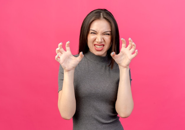 Mujer bonita joven juguetona haciendo gesto de patas de tigre aislado sobre fondo rosa con espacio de copia