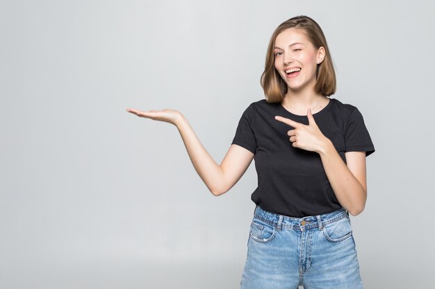 Mujer bonita joven con la palma abierta puntiaguda aislado en la pared blanca