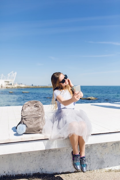 Mujer bonita joven con el pelo largo está sentado en el muelle