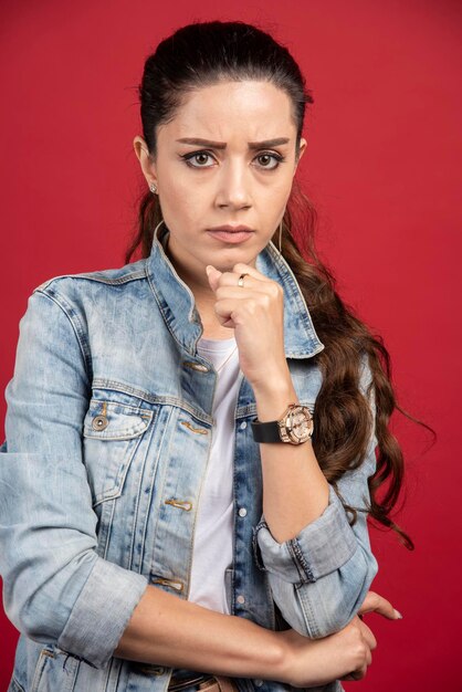 Mujer bonita joven posando en chaqueta de mezclilla sobre un fondo rojo. Foto de alta calidad