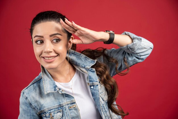 Mujer bonita joven posando en chaqueta de mezclilla sobre un fondo rojo. Foto de alta calidad